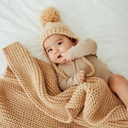 A newborn resting in a soft knitted blanket